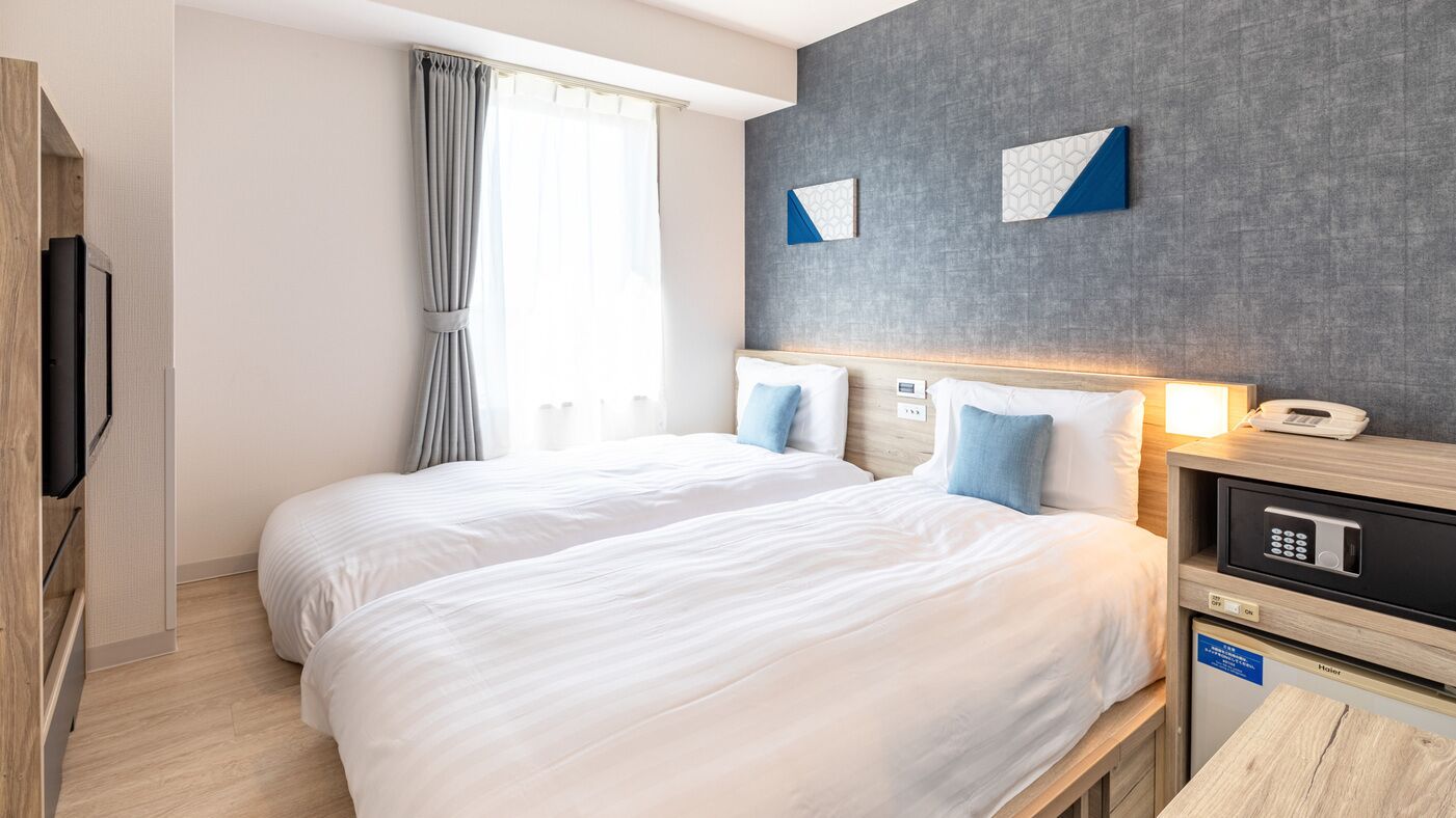 Une chambre d’hôtel avec deux lits, une télévision, un bureau avec un téléphone et un four à micro-ondes.