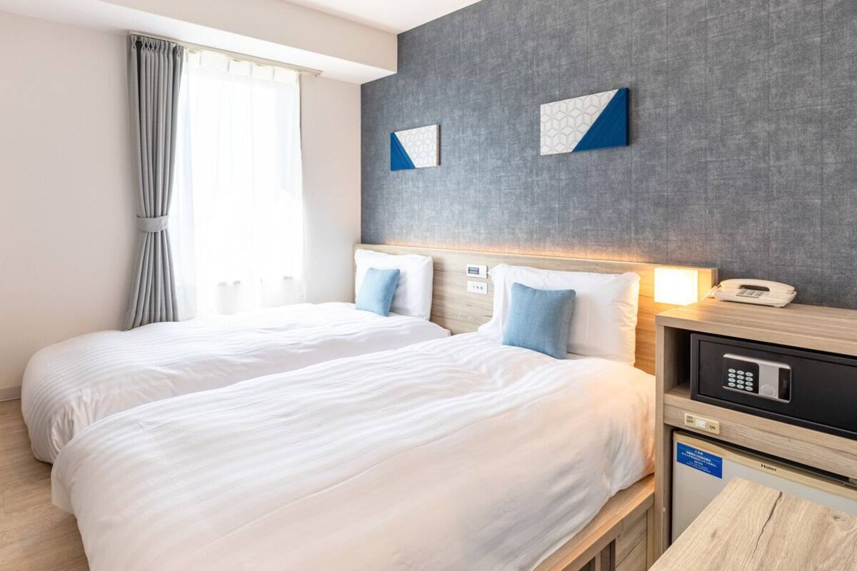 Ein Hotelzimmer mit zwei Betten, einem Fernseher, einem Schreibtisch mit Telefon und einer Mikrowelle.