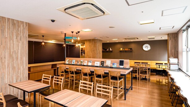 A modern restaurant with wooden tables and chairs, a bar area, and a clock on the wall. - Comfort Hotel Hiroshima Otemachi (Hiroshima)