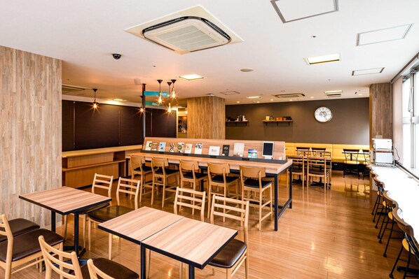 Un restaurant moderne avec des tables et des chaises en bois, un coin bar et une horloge au mur.