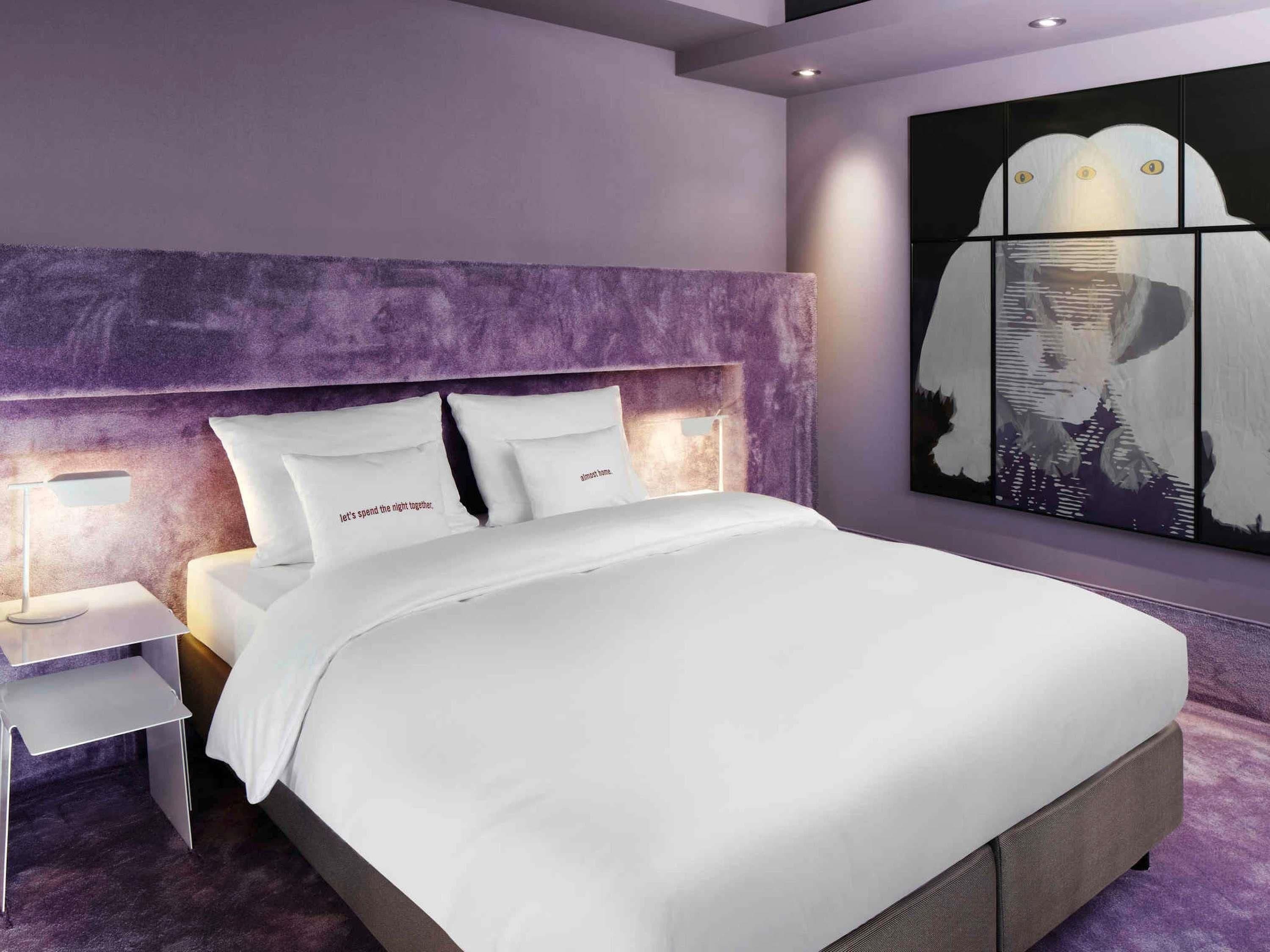 Un dormitorio moderno con una cama grande, cabecera, mesitas de noche y una obra de arte en la pared.
