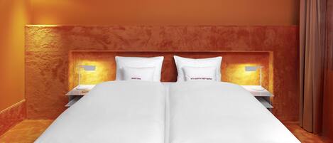 A hotel room with a large bed, two bedside tables with lamps, and a headboard with a textured design.
