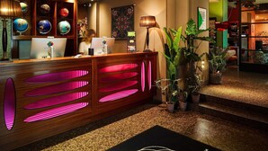 Een receptiebalie in een hotel, met een wereldbol, een bureaulamp en een plant.
