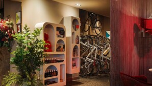 Un hall d’hôtel comprenant un espace salon, une plante, un porte-vélos et un mur orné de tableaux.