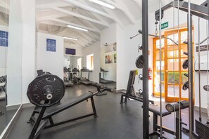 A gym with weightlifting equipment, treadmills, and a mirrored wall.