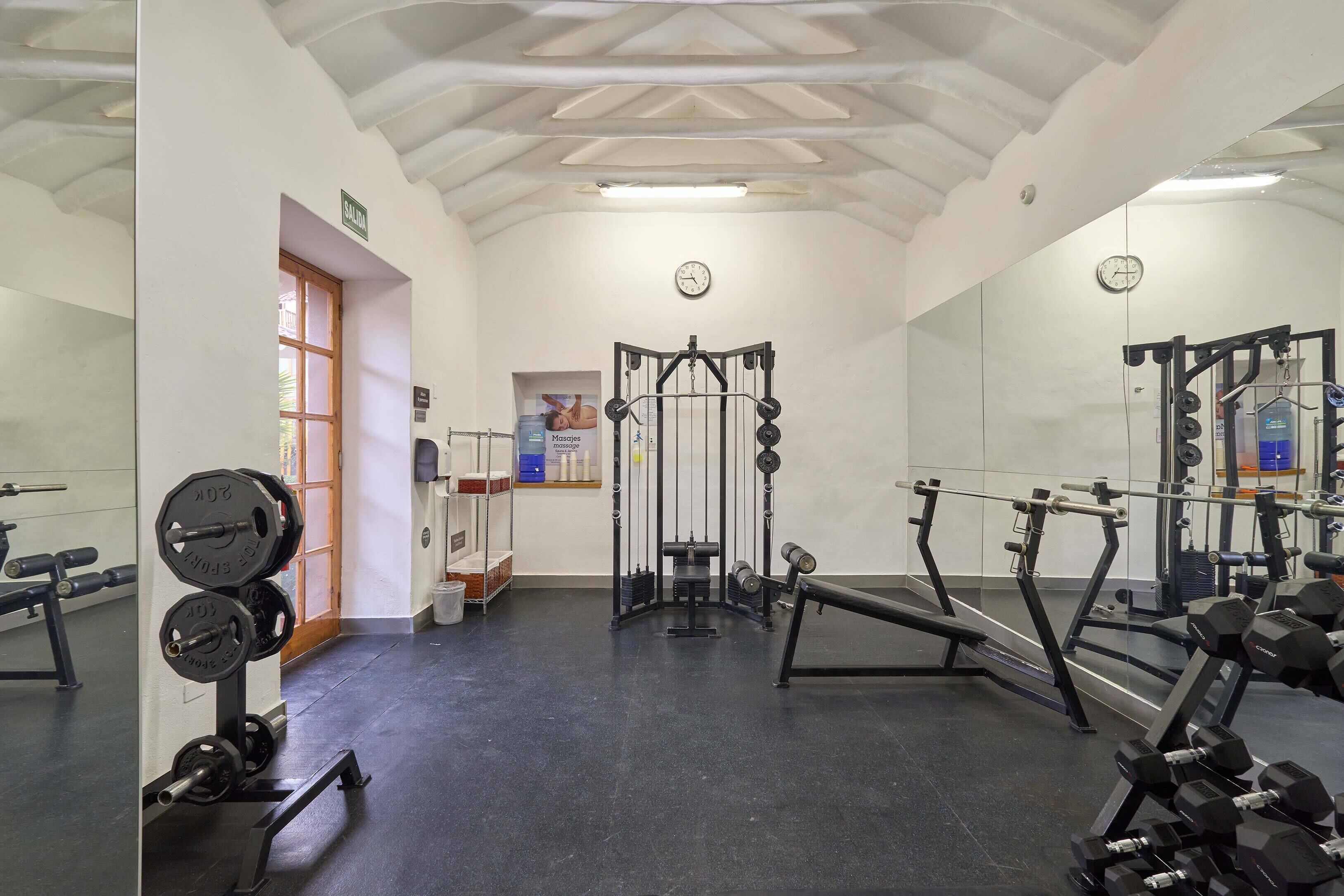 A gym with weightlifting equipment, a squat rack, and a bench.