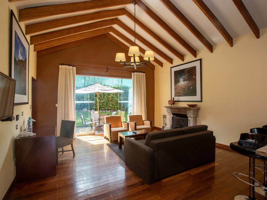 A spacious living room with wooden flooring, a fireplace, a sofa, and a dining area with a table and chairs.
