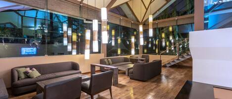 A modern interior with a wooden floor, sofas, a coffee table, and hanging lights.