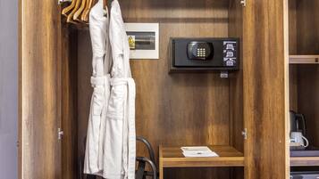 A wooden wardrobe with a built-in safe, a towel rack, and a small table with a kettle.