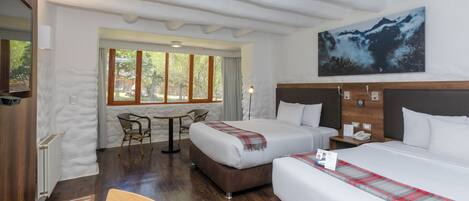 A hotel room with two beds, a dining table, and a chair.