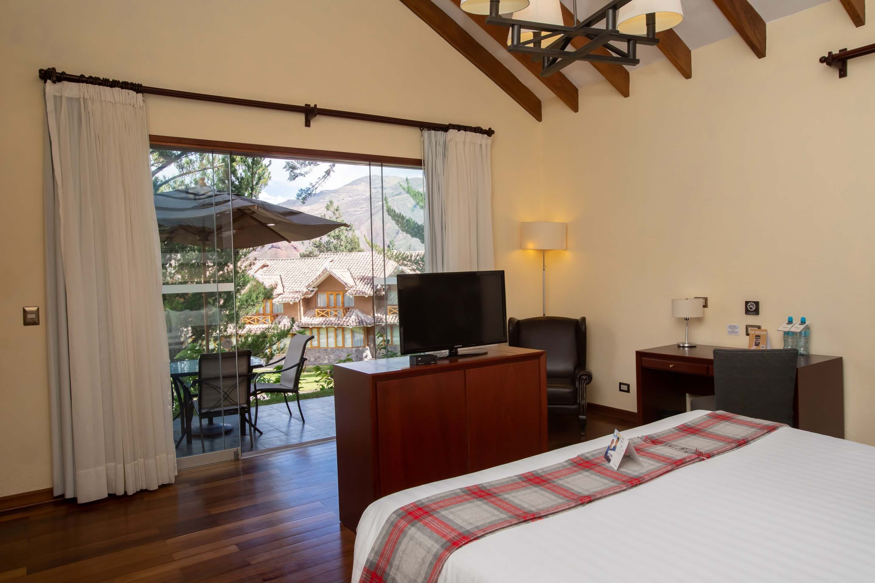 Una habitación de hotel con cama, escritorio, televisor y vistas al exterior.
