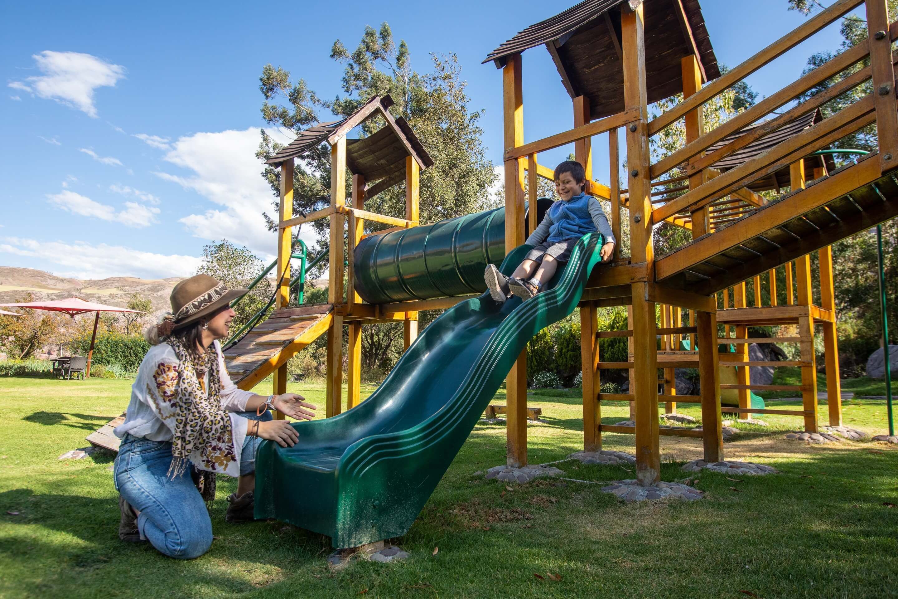 A playground with a green slide and wooden play structures.