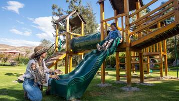 A playground with a green slide and wooden play structures.