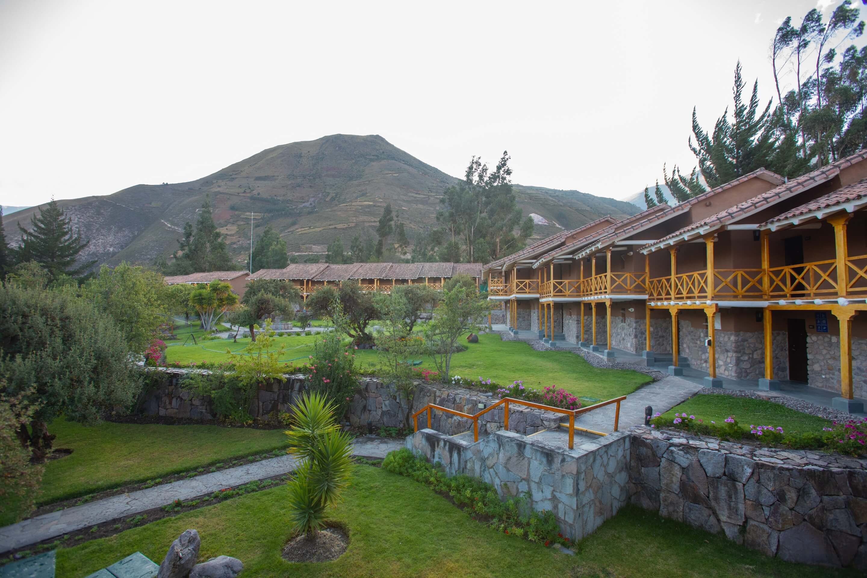 Un hotel con varias habitaciones, un sendero de piedra y montañas al fondo.