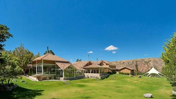 A modern resort with multiple buildings, a well-maintained lawn, and a mountainous backdrop.