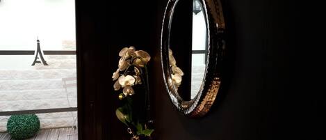 Une porte avec un miroir et un vase rempli d’orchidées blanches.