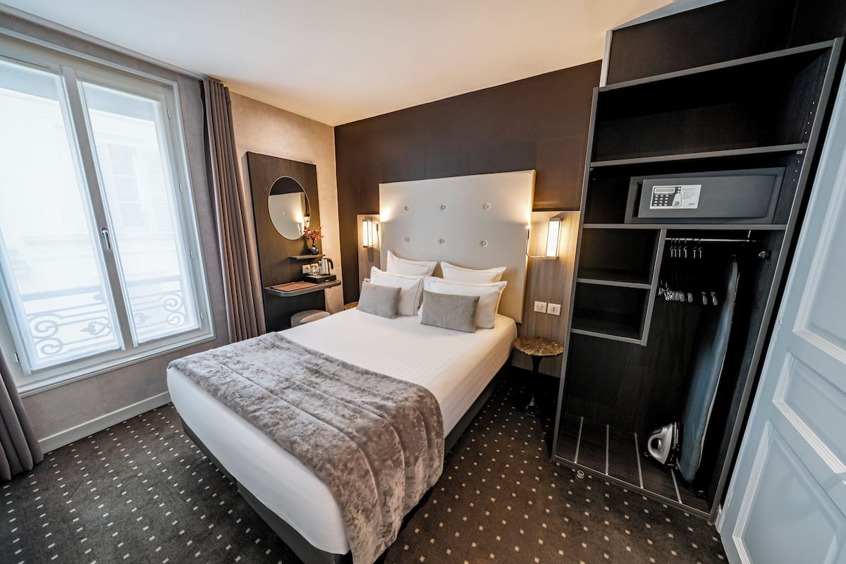 Une chambre d’hôtel avec un grand lit, une commode, un miroir et une armoire.