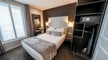 Hotellihuone, jossa on suuri sänky, lipasto, peili ja vaatekaappi.