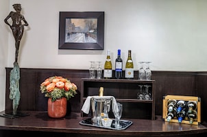A bar area with a statue, a painting, and a selection of wine bottles and glasses.