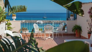 A balcony with white chairs and a table overlooking a marina with boats and the sea. - Palermo Mare Holidays (Palermo)