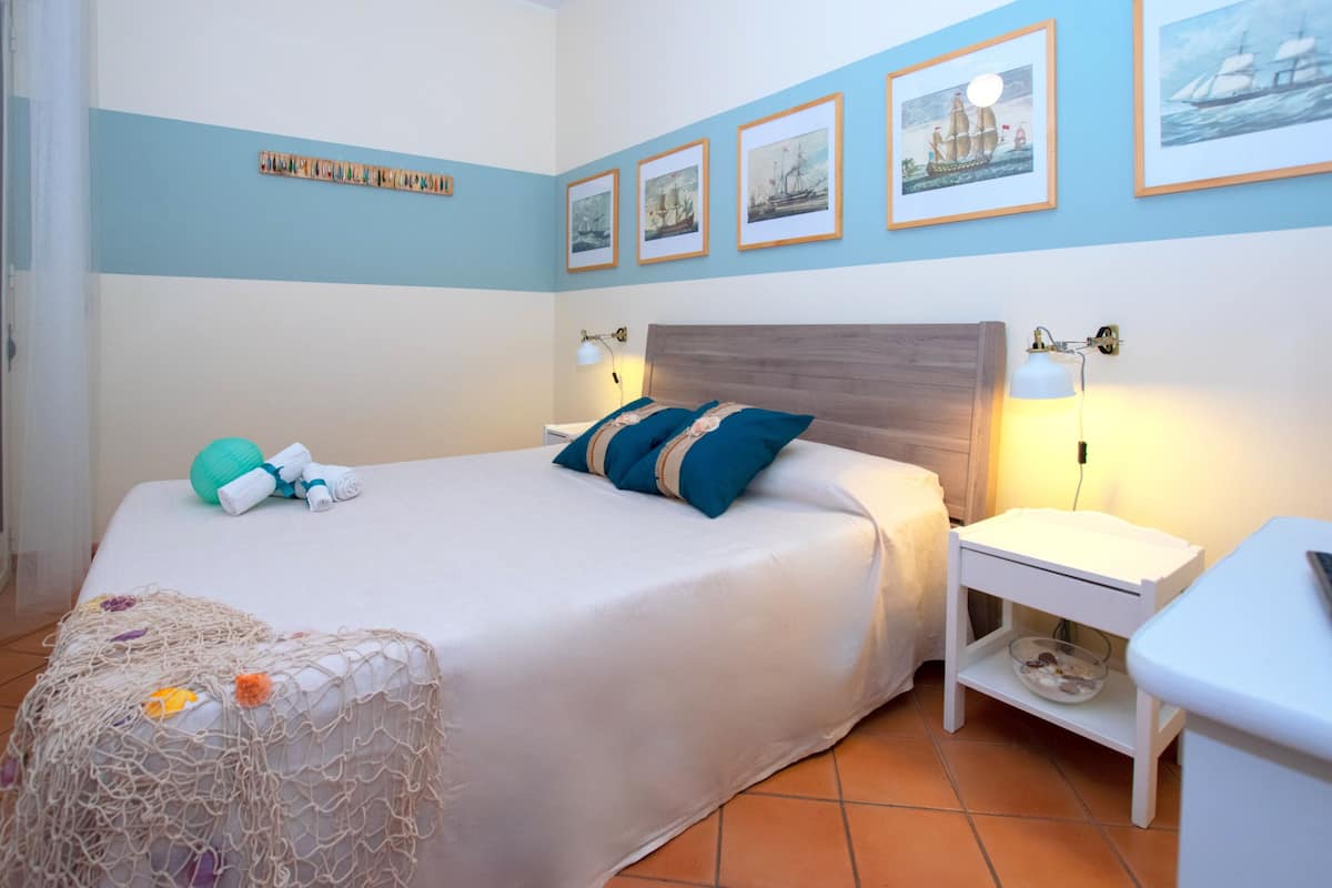 Un dormitorio ordenado con cama, mesitas de noche y lámparas de pared.