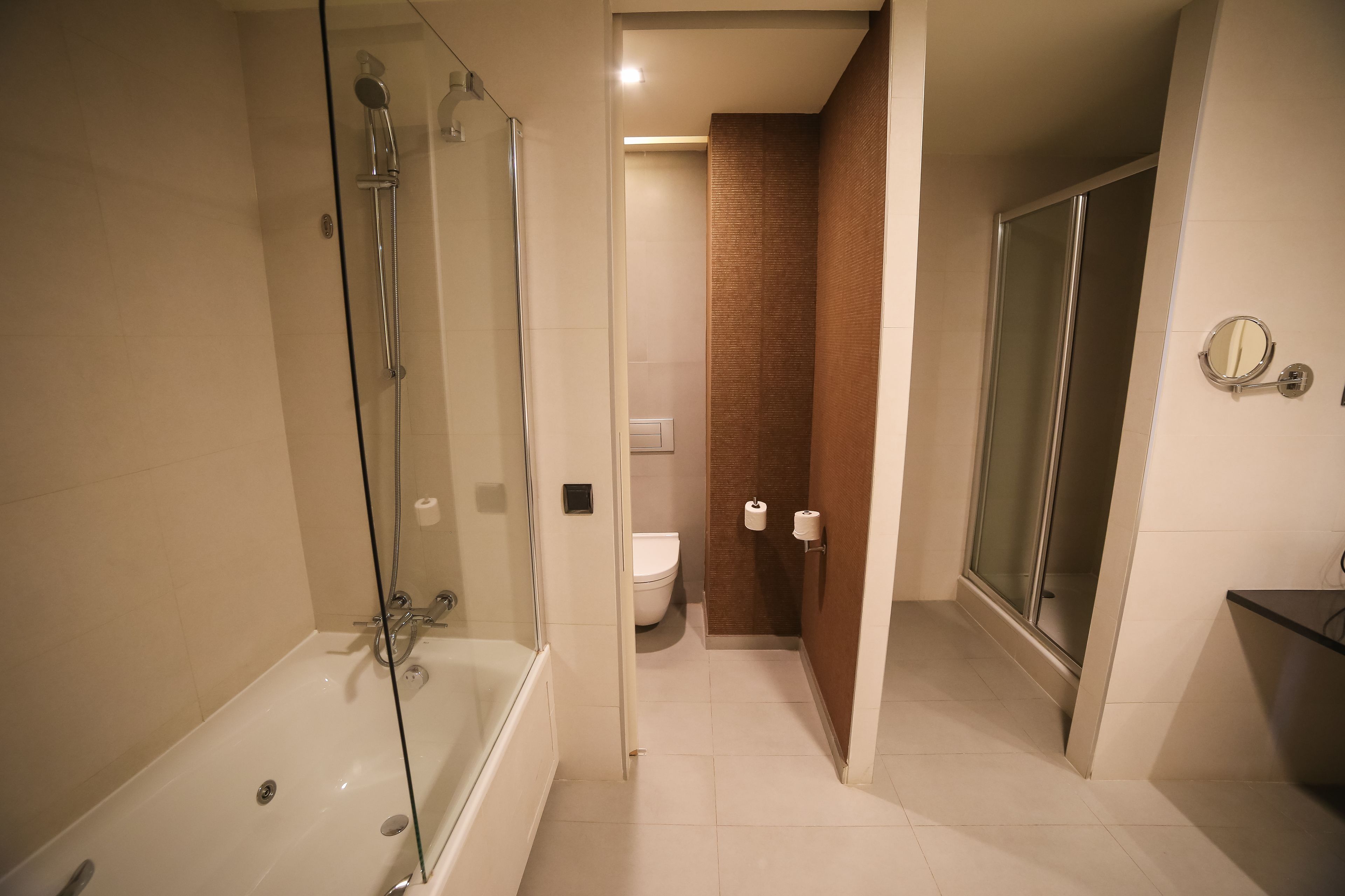 A modern bathroom with a glass-enclosed shower, a bathtub, a toilet, and a glass-enclosed shower stall.