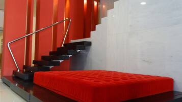 A modern room with a red bed, a staircase with metal railings, and a red accent wall.