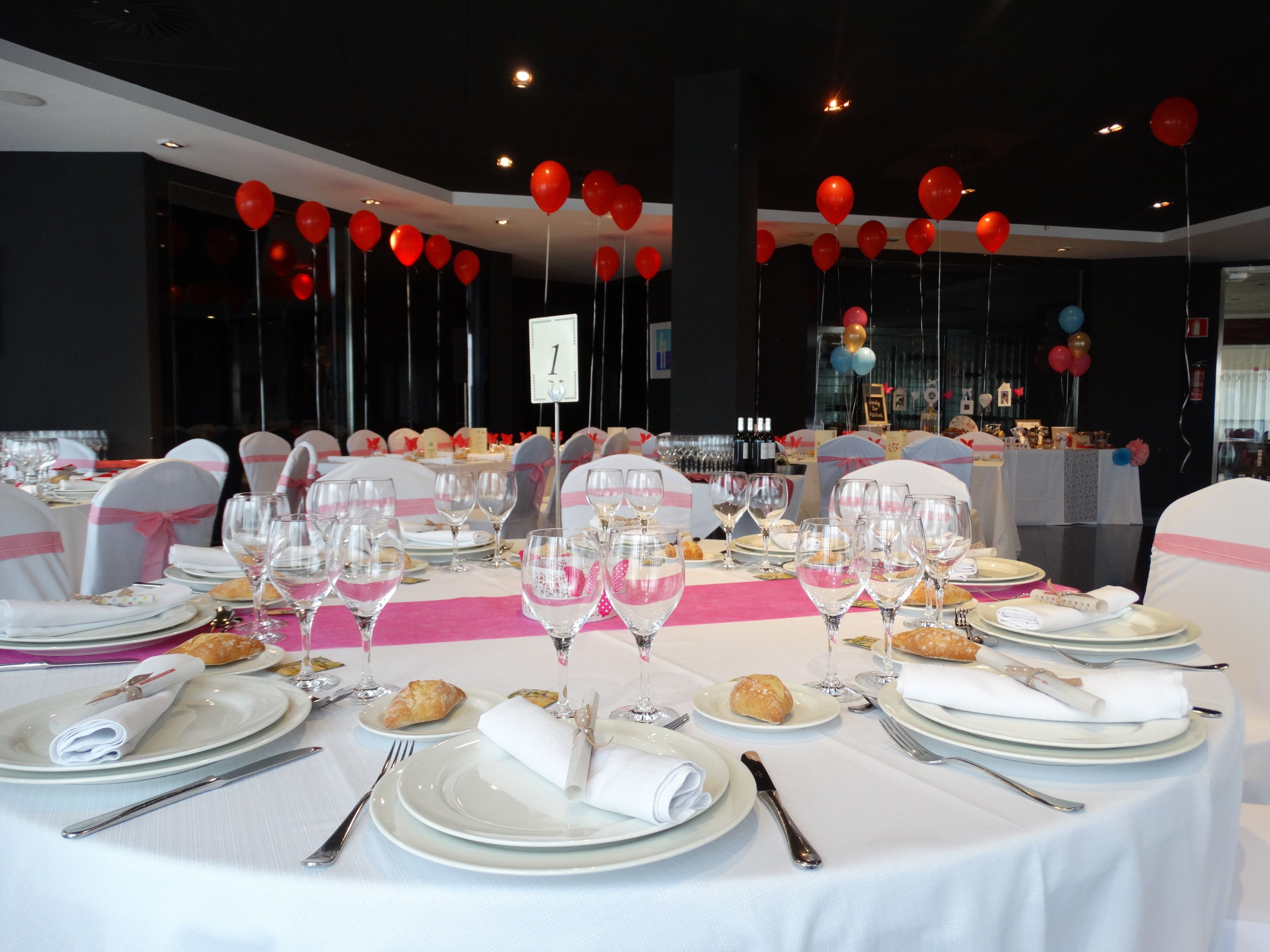 A banquet hall with round tables set for a formal event, complete with white tablecloths, plates, glasses, and cutlery.
