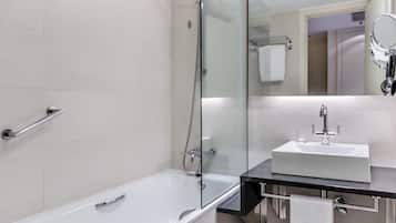 Ein modernes Badezimmer mit einer gläsernen Duschkabine, einer weißen Badewanne und einem schwarzen Waschtisch mit Spiegel darüber.