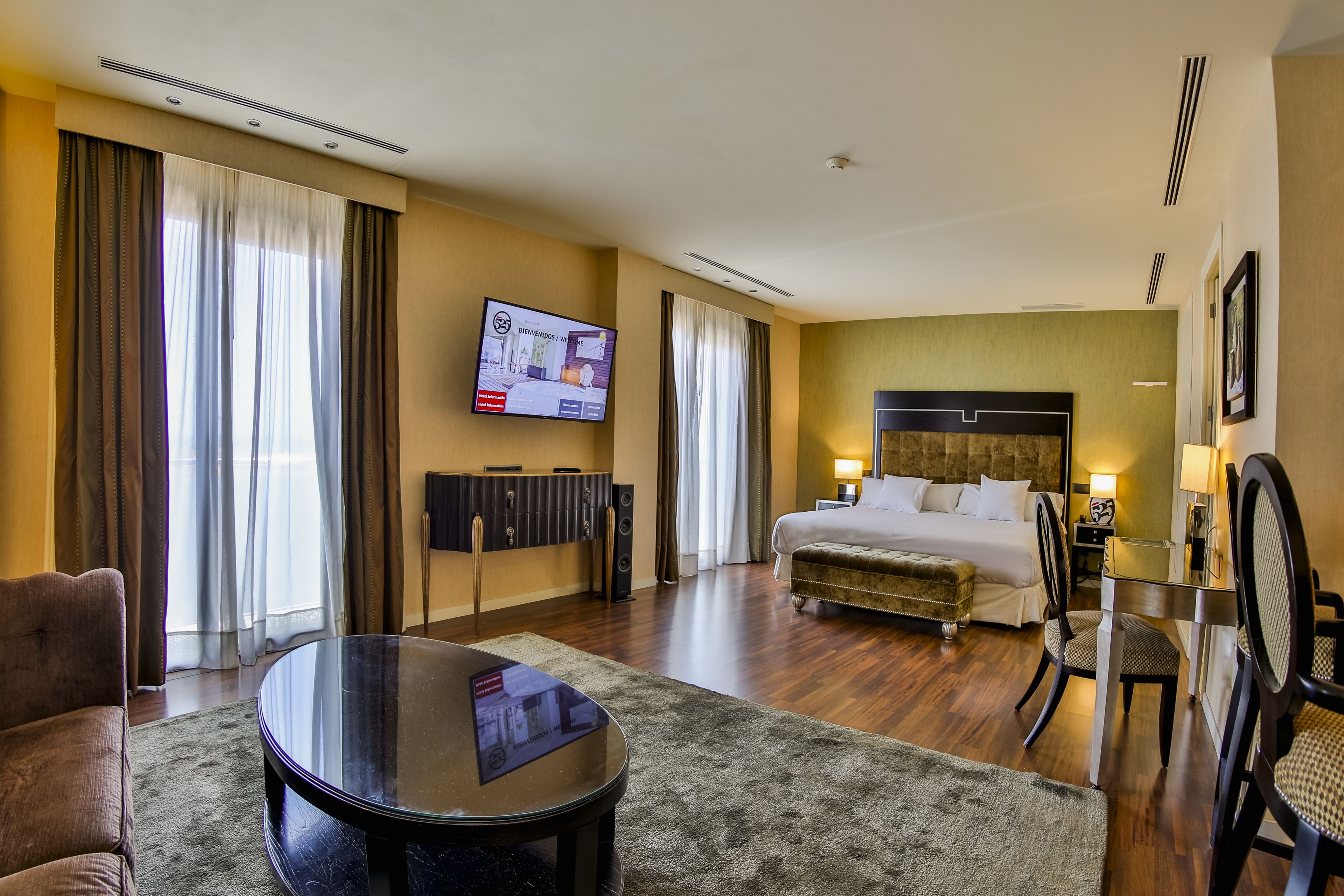 Ein Hotelzimmer mit Bett, Schreibtisch, Stuhl, Fernseher und einer Couch.