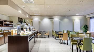 Un comedor amplio con varias mesas y sillas, una barra de buffet con diferentes alimentos, y un diseño interior moderno y elegante.