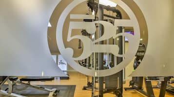 Un gimnasio con equipo de ejercicio, incluyendo una banca y máquinas de pesas.