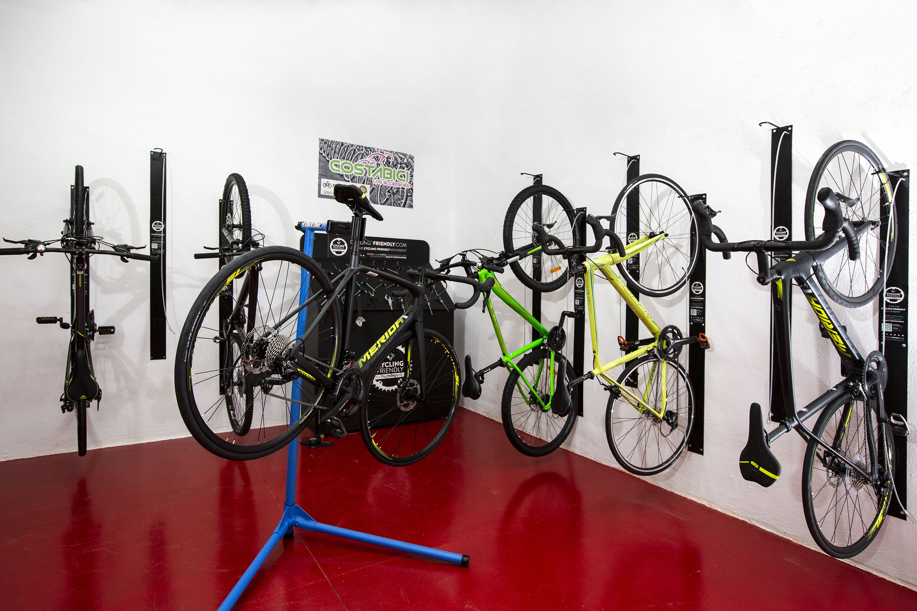Area porta bici con diverse biciclette e pavimento rosso.