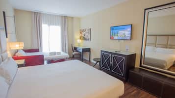 Ein Hotelzimmer mit einem großen Bett, einem Schreibtisch mit Stuhl, einem Fernseher und einem Kleiderschrank.