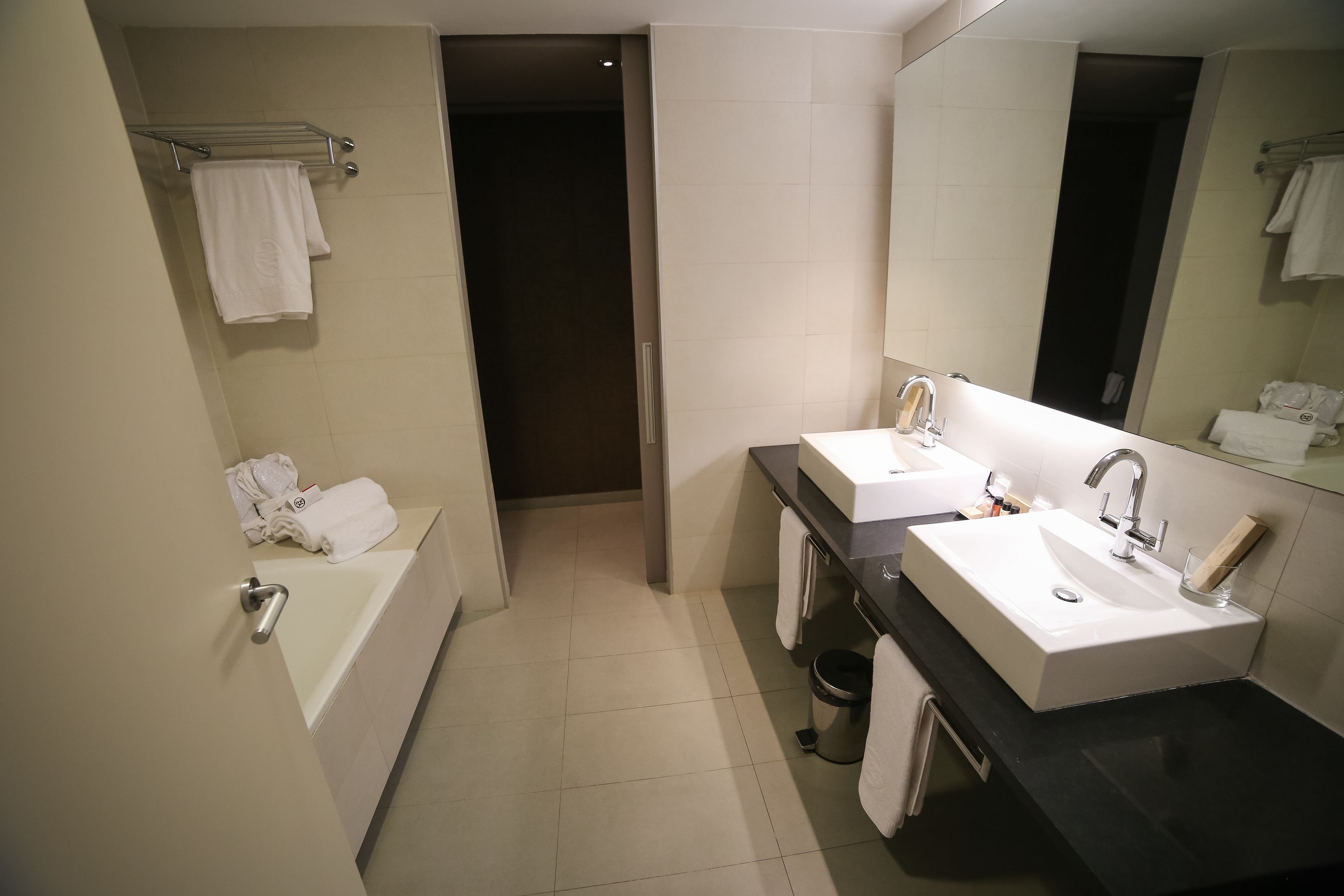 A modern bathroom with a bathtub, two sinks, and a large mirror.