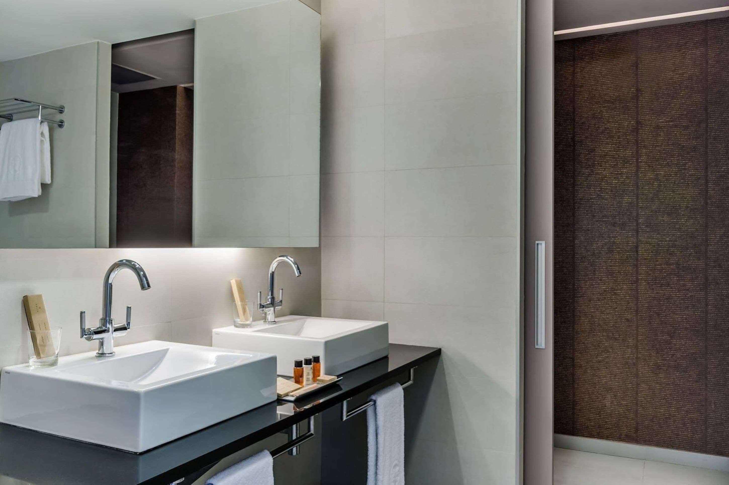Une salle de bain moderne avec deux lavabos, un grand miroir et une douche à l’italienne.