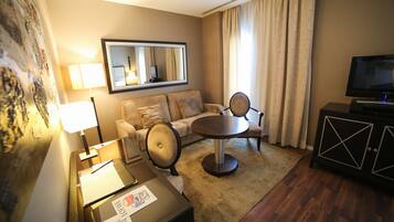 A hotel room with a sofa, a round table, a television, and a cabinet.
