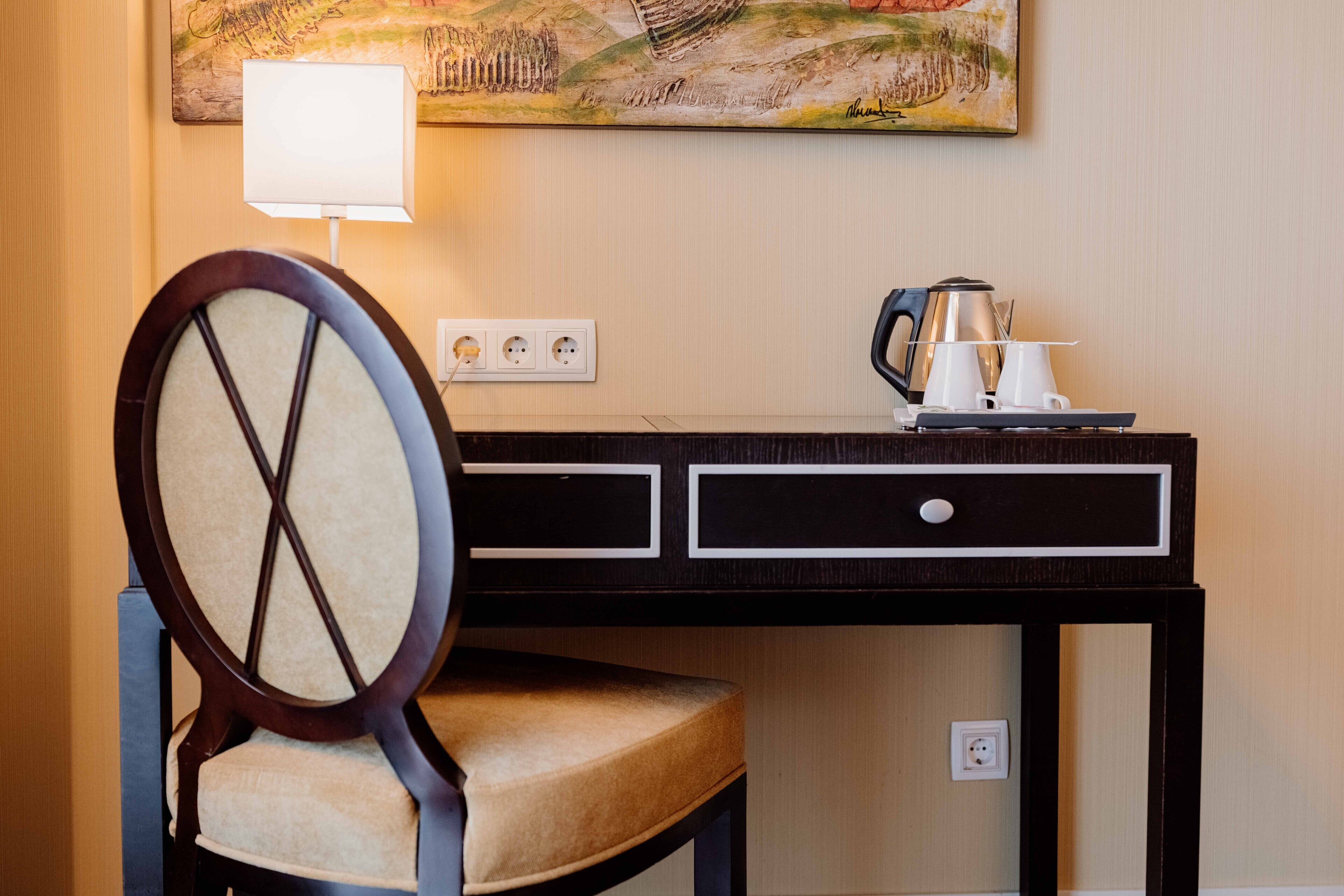 Ein Hotelzimmer mit einem Holztisch, einem Stuhl, einer Lampe und einem Bild an der Wand.