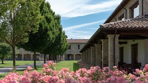 A courtyard with stone buildings, a tree, and pink flowers.