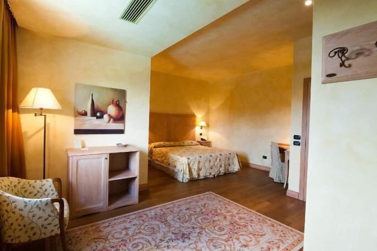 Een kamer met twee bedden, een bureau, een stoel, een lamp, een schilderij en een vloerkleed.