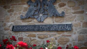 Un mur de pierres sur lequel est fixée une plaque métallique portant l’inscription « Ristorante I Due Angeli ».