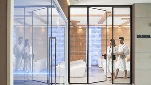 A modern spa area with glass partitions, wooden accents, and white furnishings.
