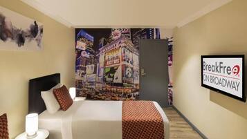 A hotel room with a bed, a nightstand, a lamp, a wall-mounted TV, and a poster of Broadway.
