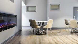 Ein moderner Konferenzraum mit Kamin, einem Tisch mit Stühlen und zwei gerahmten Bildern an der Wand.