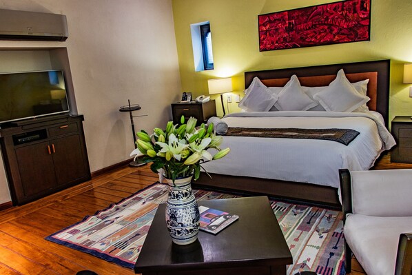 Una habitación de hotel con cama, televisión, un jarrón con flores, un escritorio y una silla.