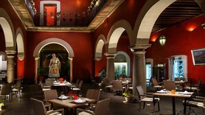 Un restaurante con paredes rojas, techos abovedados y varias mesas y sillas.