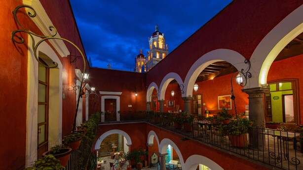 Un patio con arcos, plantas en macetas y una estatua.