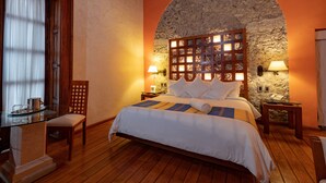 Un dormitorio con pared de piedra, muebles de madera y cama con ropa blanca.