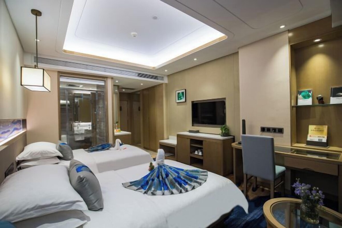 Habitación de hotel con dos camas, un escritorio, televisión y un pequeño rincón de descanso.