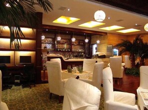 A bar area with a counter and seating, a patterned carpet, and a decorative wall. - Golden Spring Hotel (Kunming)